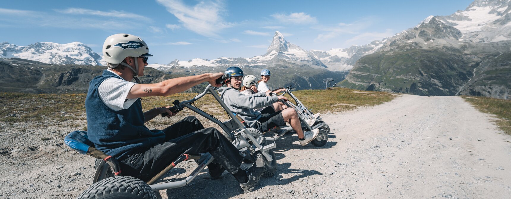 Un groupe est assis dans son mountaincarts, prêt à partir, par un temps idéal et avec une vue sur le Cervin.  | © Gabriel Perren